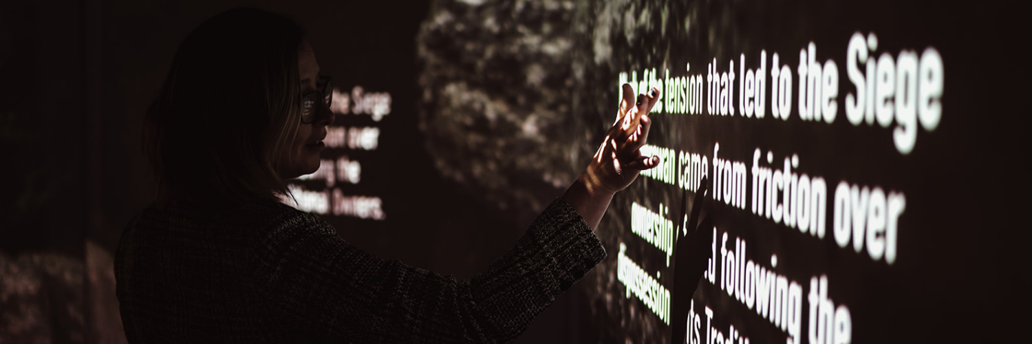 Interactive digital display at Ned Kelly Discovery Hub showing highlighted text about the tension leading to the Glenrowan siege.